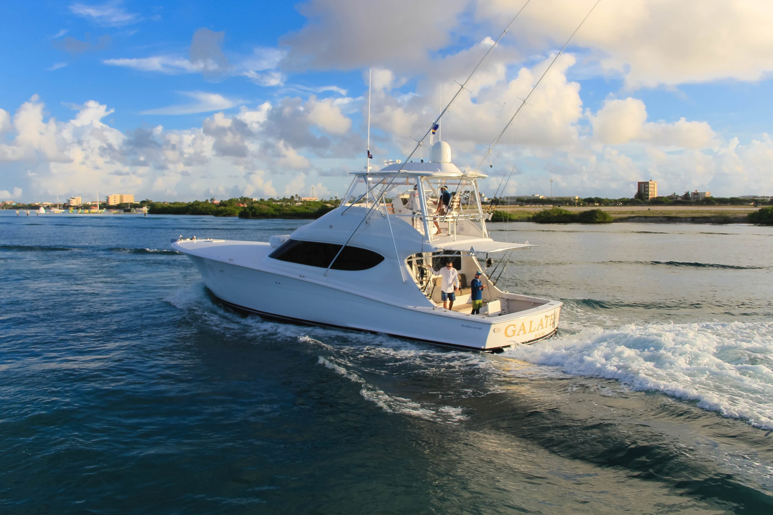 White fishing boat on water under blue sky with clouds.