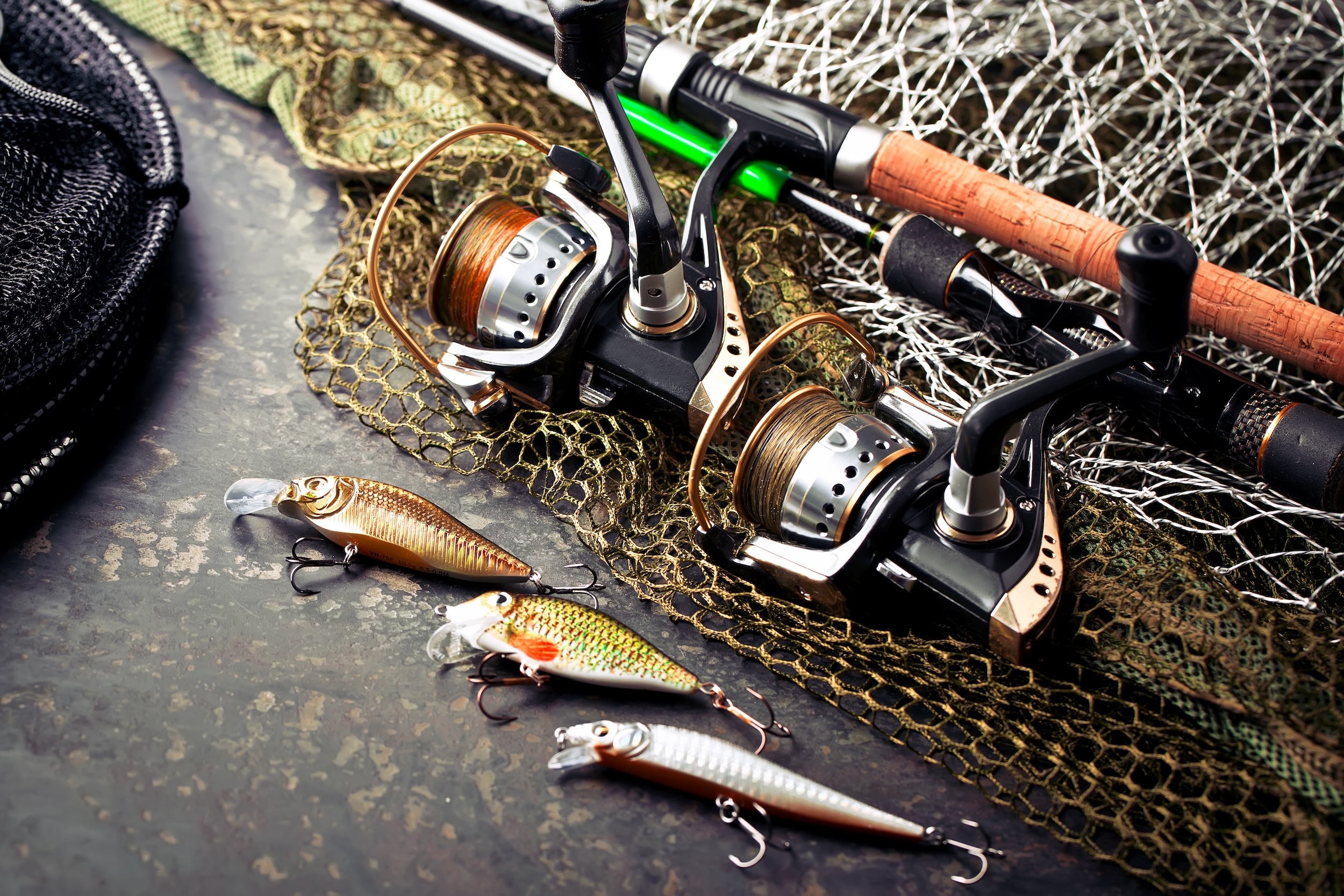 Fishing rods and lures on a net-covered surface.